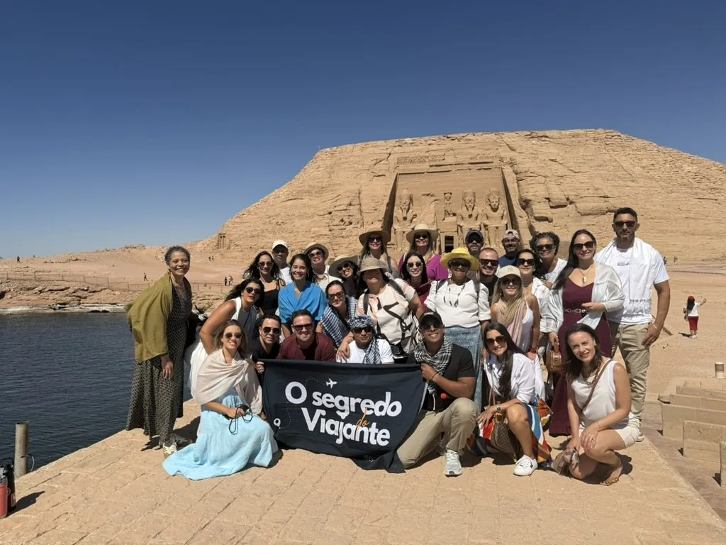 Grupo da comunidade OSV com a bandeira O Segredo do Viajante em frente ao templo de Abu Simbel, no Egito